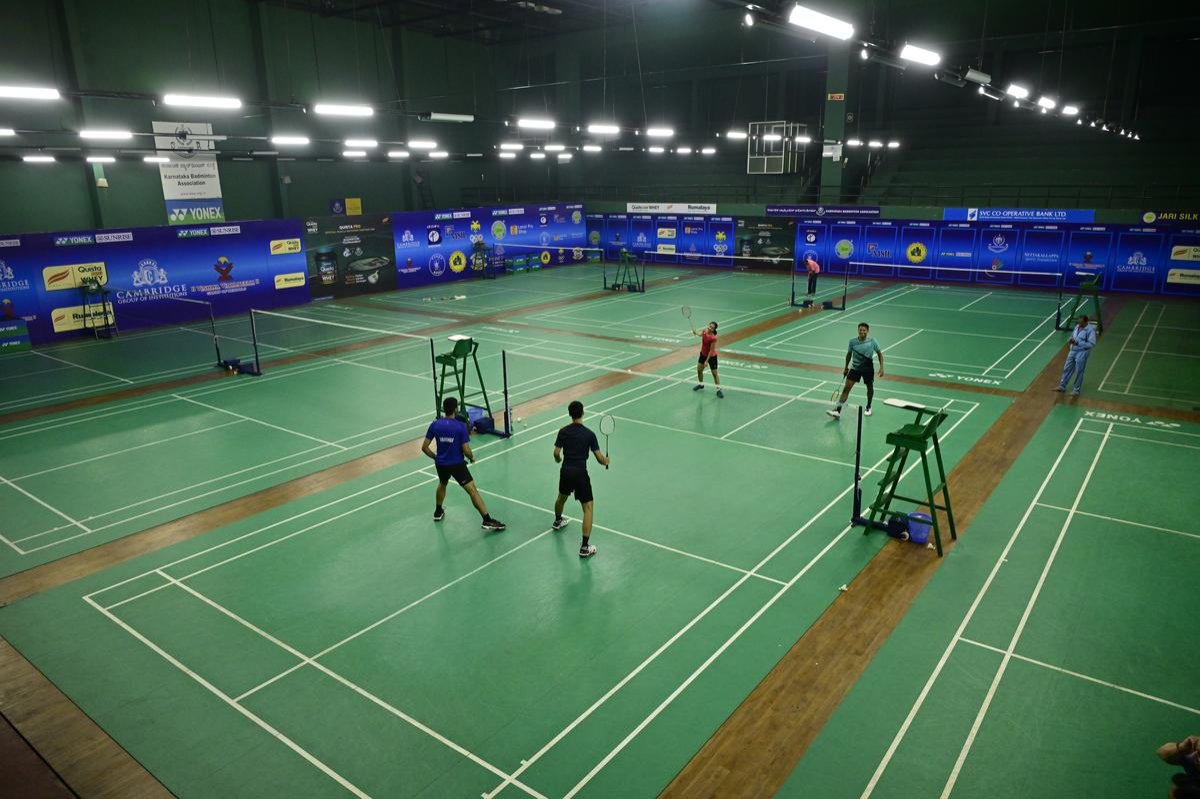 Basketball player mid-air during a dunk with stadium lights in background